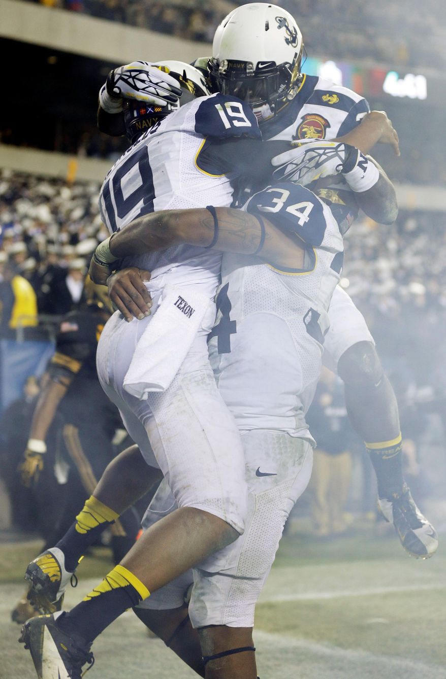 Navy's Keenan Reynolds (19) celebrates a touchdown with Noah Copeland (34) and Gee Gee Greene, top, during the second half of an NCAA college football game against Army, Saturday, Dec. 8, 2012, in Philadelphia. Navy won 17-13. (AP Photo/Matt Rourke)