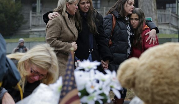 Women embrace at the site of a makeshift memorial for school shooting victims at the village of Sandy Hook in Newtown, Conn., on Sunday, Dec. 16, 2012. A gunman opened fire at Sandy Hook Elementary School in the town, killing 26 people, including 20 children, before killing himself on Friday. (AP Photo/Charles Krupa)