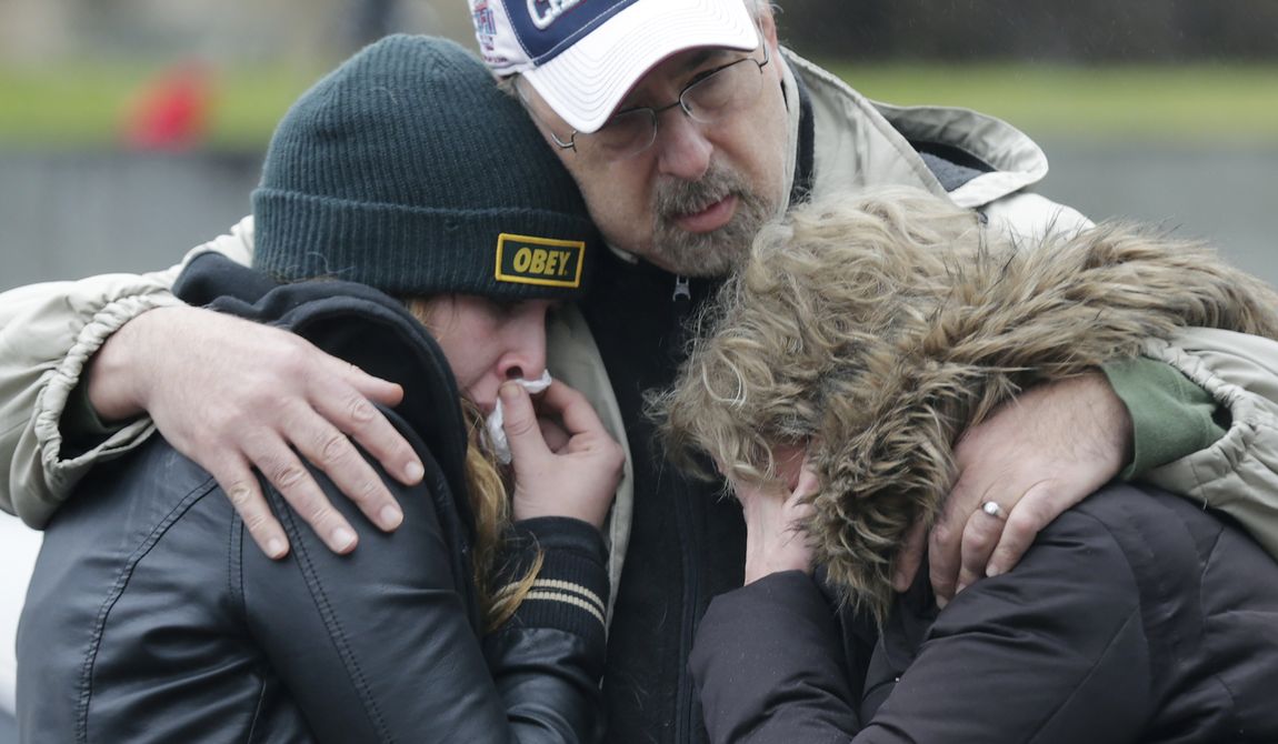 A man clutches two sobbing women at the site of a makeshift memorial for school shooting victims at the village of Sandy Hook in Newtown, Conn., on Sunday, Dec. 16, 2012. A gunman opened fire at the Sandy Hook Elementary School, killing 26 people, including 20 children, before killing himself on Friday. (AP Photo/Charles Krupa)

