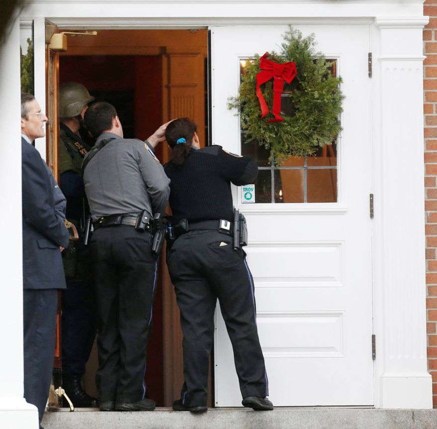 Newtown Police Officer Maryhelen McCarthy, right, looks into St. Rose of Lima Roman Catholic Church with other officials while responding to a threat, Sunday, Dec. 16, 2012, in Newtown, Conn. Worshippers hurriedly left the church on Sunday, saying they were told there was a bomb threat, not far from the elementary school where 20 kids and six adults were massacred on Friday. The all-clear was given after an hour in which armed police in SWAT gear searched the church and adjacent buildings. (AP Photo/Julio Cortez)