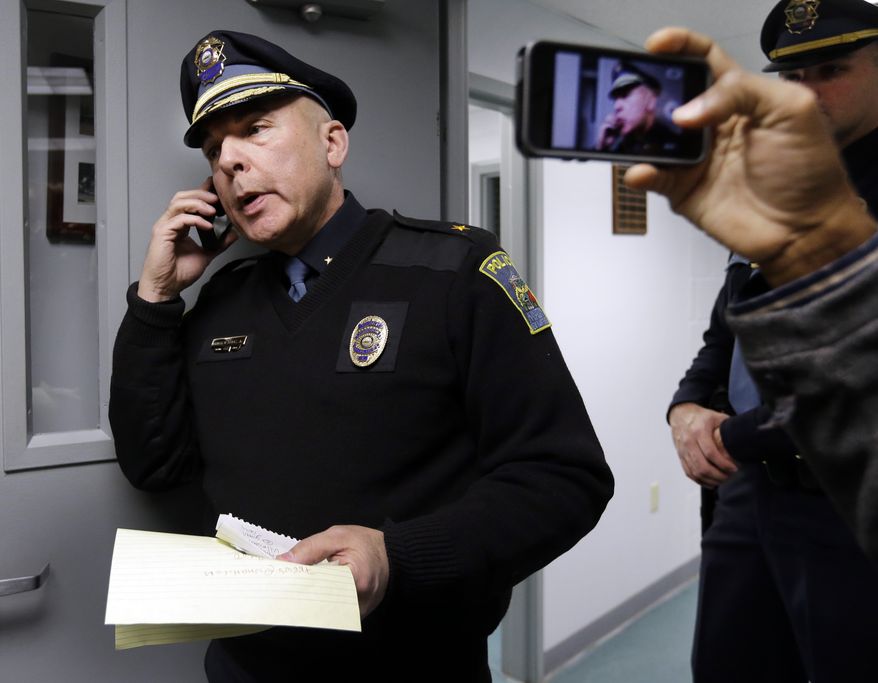 Kingston, N.H. Police Chief Donald Briggs Jr. speaks on his cellphone and relays information to members of the media at police headquarters in Kingston, N.H., Saturday, Dec. 15, 2012, as he talks with part-time Kingston Police Officer James Champion, brother of slain Nancy Lanza. (AP Photo/Elise Amendola)