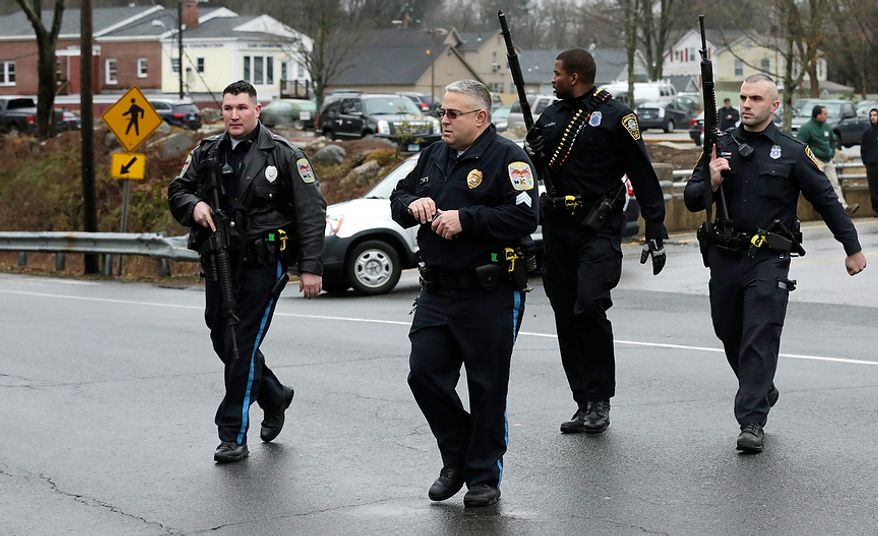 Police officers cross the road after searching a strip mall near an elementary school that was in a lockdown in Ridgefield, Conn., on Monday, Dec. 17, 2012, after a suspicious person was seen near a train station close by. On Friday, authorities say, a gunman killed his mother at their home and then opened fire inside the Sandy Hook Elementary School in Newtown, Conn., killing 26 people, including 20 children, before taking his own life. (AP Photo/Charles Krupa)