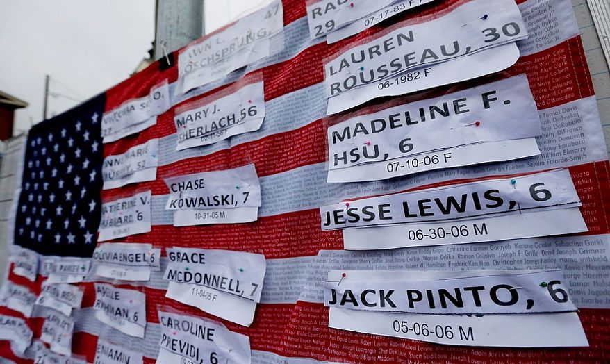 Names of victims hang on a U.S. flag on a makeshift memorial in the Sandy Hook village of Newtown, Conn., on Monday, Dec. 17, 2012, as the town mourns those killed in Friday's school shooting. (AP Photo/Julio Cortez)
