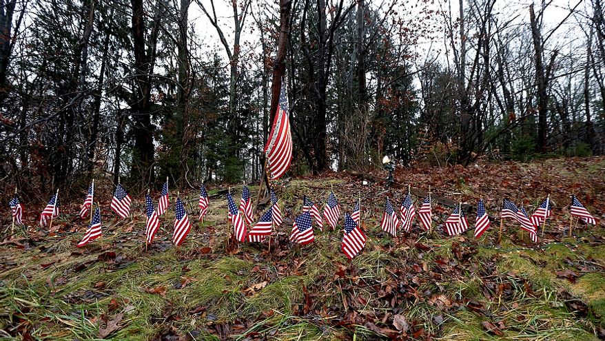Twenty-seven small U.S. flags adorn a large flag on a makeshift memorial on the side of Highway 84 near the Newtown, Conn., town line on Monday, Dec. 17, 2012, as residents mourn those killed by gunman Adam Lanza. (AP Photo/Julio Cortez)