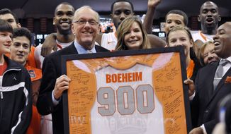 Syracuse coach Jim Boeheim, joined by his wife, Julie, is presented with a jersey for his 900th career win, after Syracuse defeated Detroit 72-68 in an NCAA college basketball game in Syracuse, N.Y., Monday, Dec. 17, 2012. (AP Photo/Kevin Rivoli)