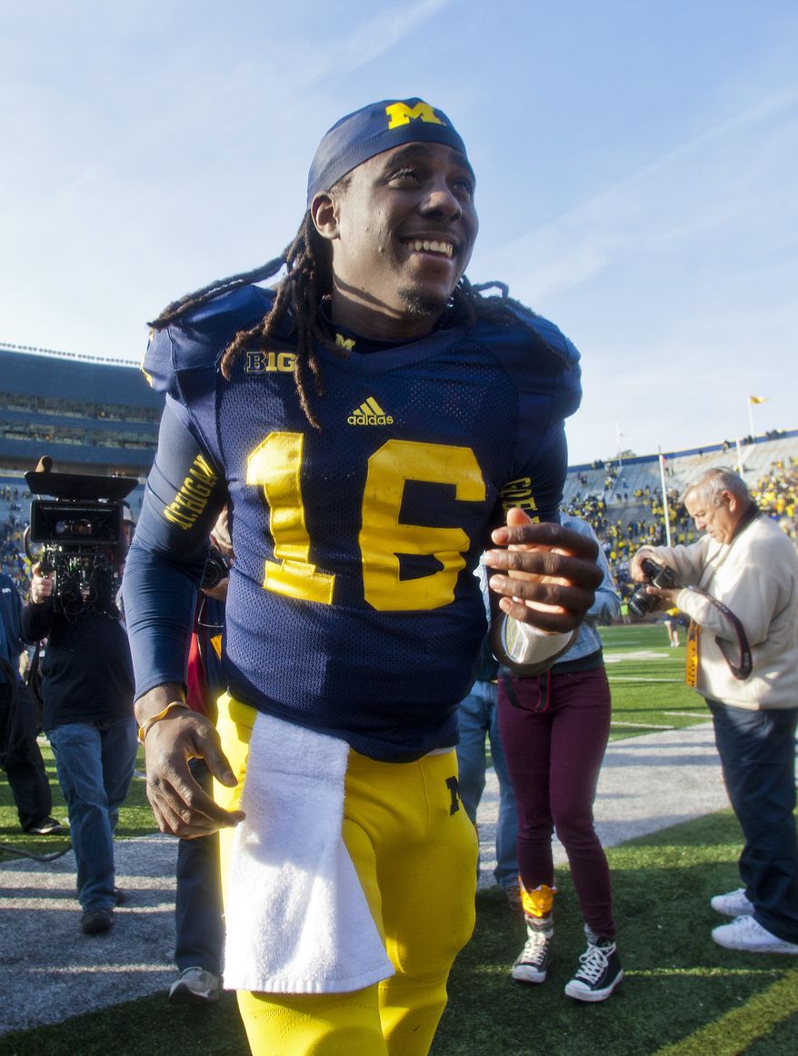 Michigan quarterback Denard Robinson (16) makes his way off the Michigan Stadium field after an NCAA college football game against Iowa, Saturday, Nov. 17, 2012, in Ann Arbor, Mich. Michigan won 42-17. (AP Photo/Tony Ding)