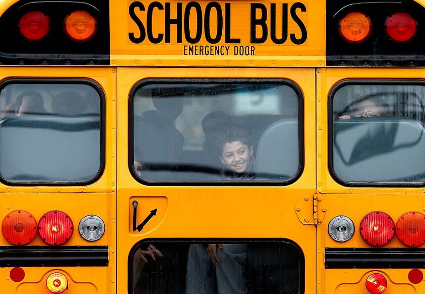 A returning student smiles as his bus school bus pulls into Hawley School, Tuesday, Dec. 18, 2012, in Newtown, Conn. Classes resume Tuesday for Newtown schools except those at Sandy Hook. Buses ferrying students to schools were festooned with large green and white ribbons on the front grills, the colors of Sandy Hook. At Newtown High School, students in sweatshirts and jackets, many wearing headphones, betrayed mixed emotions. Adam Lanza walked into Sandy Hook Elementary School in Newtown, Friday and opened fire, killing 26 people, including 20 children, before killing himself.(AP Photo/Jason DeCrow)