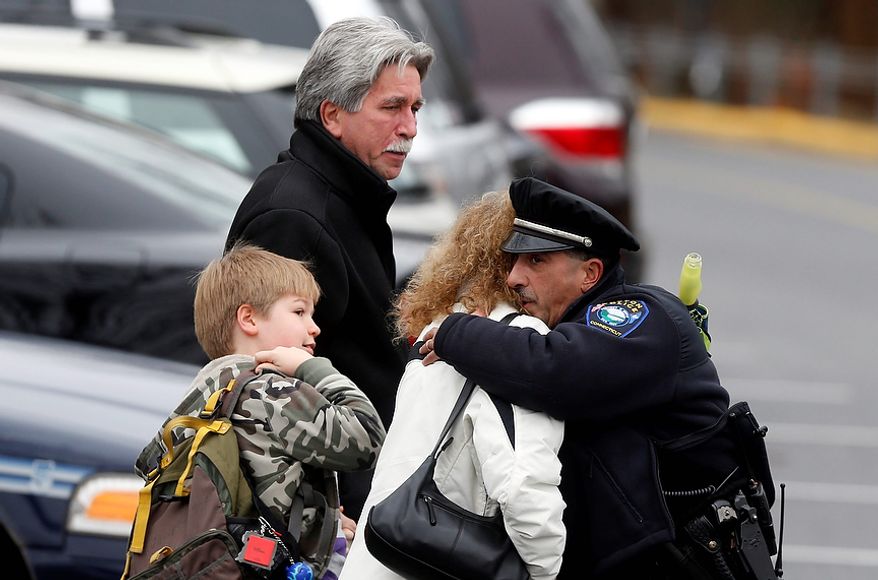 Easton police officer J. Sollazzo embraces a couple walking a young student into Hawley School, Tuesday, Dec. 18, 2012, in Newtown, Conn. Classes resume Tuesday for Newtown schools except those at Sandy Hook. Buses ferrying students to schools were festooned with large green and white ribbons on the front grills, the colors of Sandy Hook. At Newtown High School, students in sweatshirts and jackets, many wearing headphones, betrayed mixed emotions. Adam Lanza walked into Sandy Hook Elementary School in Newtown, Friday and opened fire, killing 26 people, including 20 children, before killing himself.(AP Photo/Jason DeCrow)