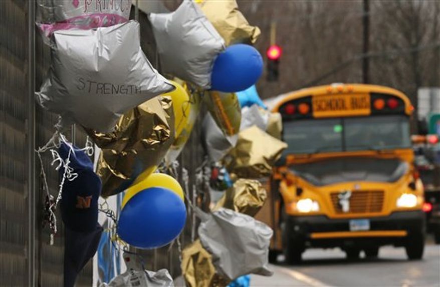 A school bus rolls towards a memorial for victims of the school shooting in Newtown, Conn., Tuesday, Dec. 18, 2012. Classes resume Tuesday for Newtown schools except those at Sandy Hook. Buses ferrying students to schools were festooned with large green and white ribbons on the front grills, the colors of Sandy Hook. At Newtown High School, students in sweatshirts and jackets, many wearing headphones, betrayed mixed emotions. Adam Lanza walked into Sandy Hook Elementary School in Newtown, Friday and opened fire, killing 26 people, including 20 children, before killing himself. (AP Photo/Charles Krupa)