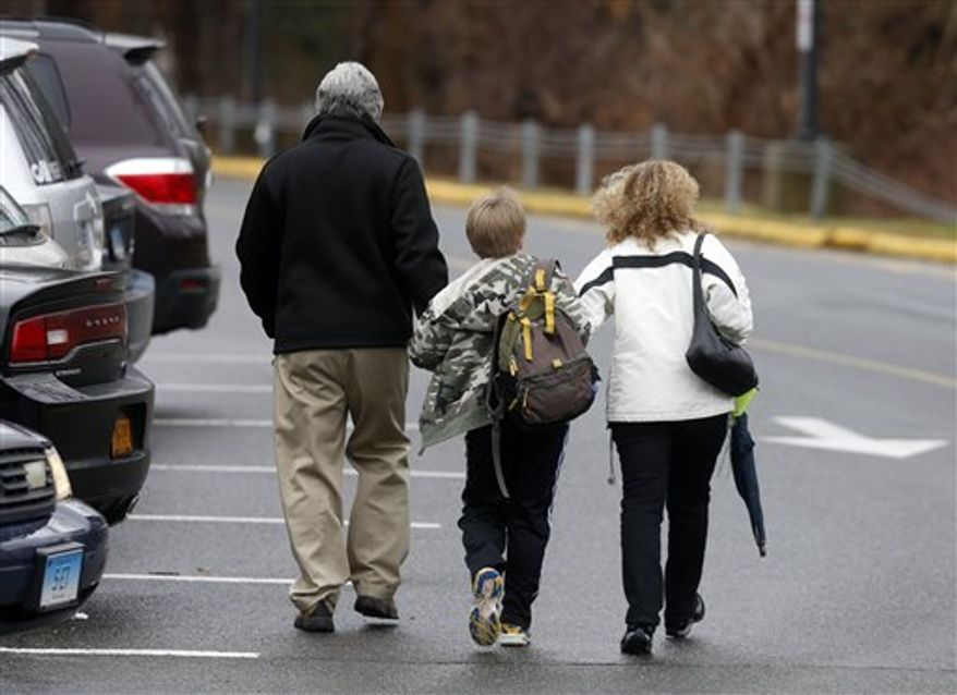 A young student is walked into Hawley School, Tuesday, Dec. 18, 2012, in Newtown, Conn. Classes resume Tuesday for Newtown schools except those at Sandy Hook. Buses ferrying students to schools were festooned with large green and white ribbons on the front grills, the colors of Sandy Hook. At Newtown High School, students in sweatshirts and jackets, many wearing headphones, betrayed mixed emotions. Adam Lanza walked into Sandy Hook Elementary School in Newtown, Friday and opened fire, killing 26 people, including 20 children, before killing himself.(AP Photo/Jason DeCrow)