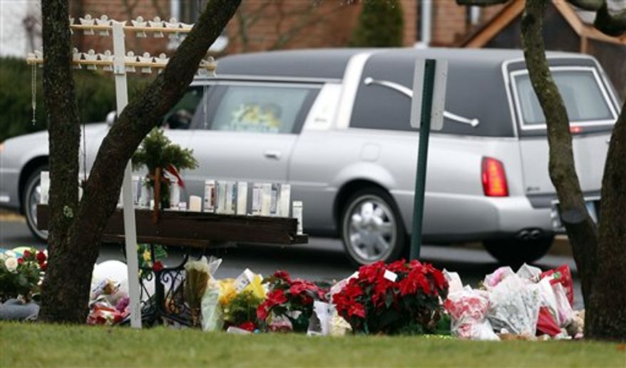 A makeshift memorial stands outside of St. Rose of Lima Roman Catholic Church as the hearse carrying the body of James Mattioli, Tuesday, Dec. 18, 2012, in Newtown, Conn. Mattioli, 6, was killed when Adam Lanza walked into Sandy Hook Elementary School in Newtown, Conn., Dec. 14, and opened fire, killing 26 people, including 20 children, before killing himself.(AP Photo/Julio Cortez)