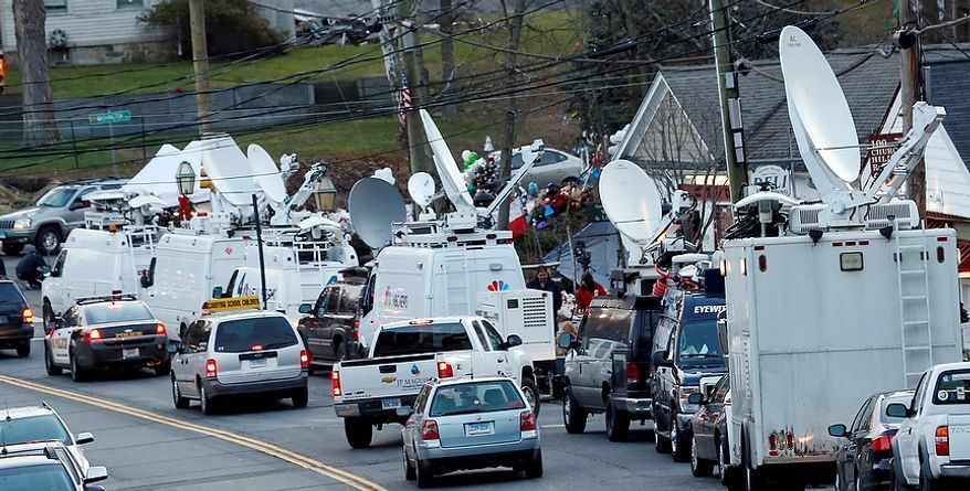 A van with a sign reading "carrying school children", center left, drives behind a police vehicle through a main road in the Sandy Hook village of Newtown, Conn., as the strong media presence is felt in the aftermath of the elementary school shooting that shocked the small, quiet town, Wednesday, Dec. 19, 2012. News about the shooting spread quickly across the world, prompting media outlets to set camp in the small town. The gunman, Adam Lanza, walked into Sandy Hook Elementary School in Newtown, Conn., Dec. 14, and opened fire, killing 26 people, including 20 children, before killing himself. (AP Photo/Julio Cortez)