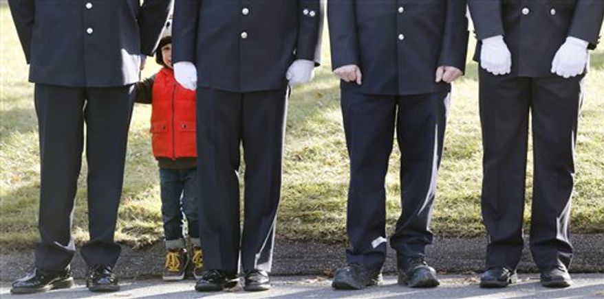 A child peers through firefighters standing as the procession heads to the cemetery outside the funeral for school shooting victim Daniel Gerard Barden at St. Rose of Lima Catholic Church in Newtown, Conn., Wednesday, Dec. 19, 2012. According to firefighters, Daniel wanted to be a firefighter when he grew up and they honored him at the service. Barden, 7, was killed when Adam Lanza walked into Sandy Hook Elementary School in Newtown, Conn., Dec. 14, and opened fire, killing 26 people, including 20 children, before killing himself. (AP Photo/Charles Krupa)