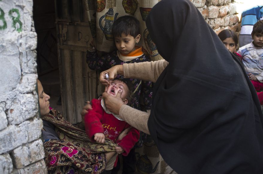 A Pakistani polio worker administers the oral polio vaccine to an infant in a Christian colony in the slums of Islamabad on Wednesday, Dec. 19, 2012. (AP Photo/B.K. Bangash)
