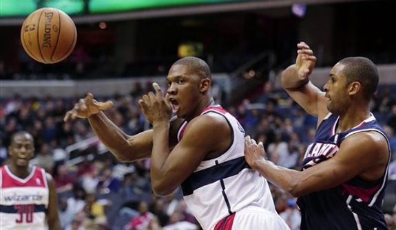 Washington Wizards forward Kevin Seraphin passes the ball in front ot Atlanta Hawks center Al Horford during the second half of an NBA game Tuesday, Dec. 18, 2012, in Washington. The Hawks won 100-95 in overtime. (AP Photo/Alex Brandon)