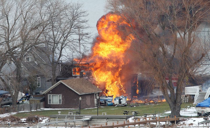 A house burns Monday in Webster, N.Y., a suburb of Rochester on Lake Ontario. A 62-year-old ex-convict set a car and a house ablaze in the neighborhood to lure firefighters before opening fire on them, slaying two. (Associated Press)