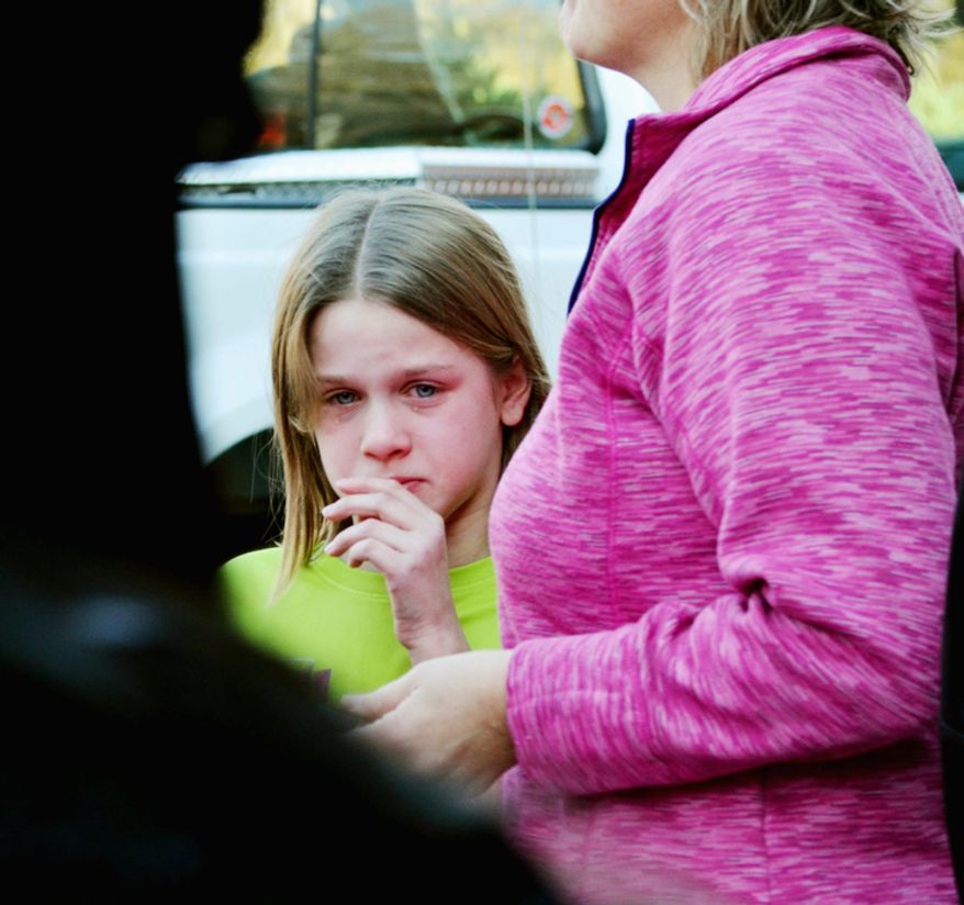 A young girl cries following the mass shooting at the Sandy Hook Elementary School in Newtown, Conn., about 60 miles northeast of New York, on Friday, Dec. 14, 2012. (AP Photo/The New Haven Register, Melanie Stengel)