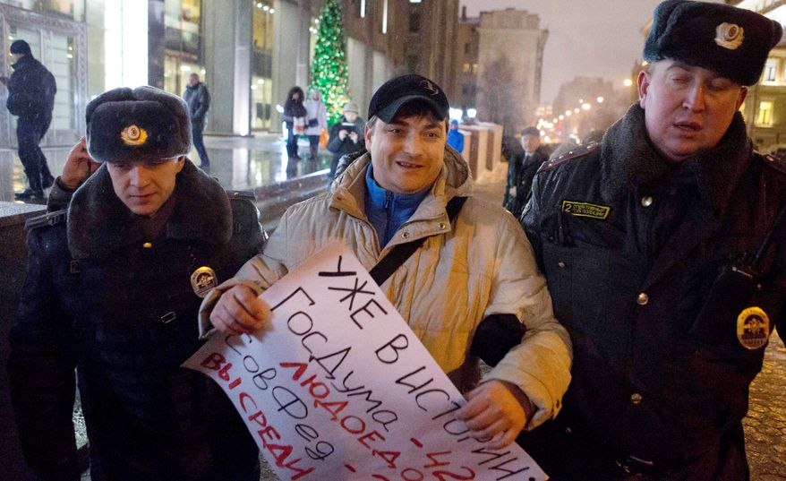 Russian police officers detain a demonstrator protesting against a bill banning U.S. adoptions of Russian children outside the Russian parliament’s upper chamber in Moscow on Wednesday. The chamber unanimously voted in favor of the measure. (Associated Press)