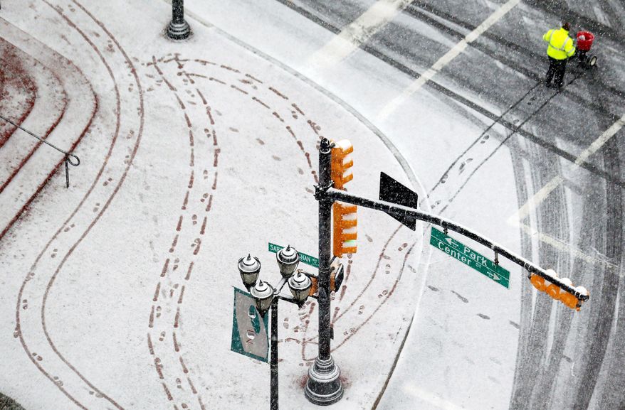 A person salts the sidewalk in downtown Newark, N.J., on Wednesday. Forecasts called for 12 to 18 inches of snow inland from western New York to Maine starting late Wednesday into Thursday, then tapering off into a mix of rain and snow closer to the coast. (Associated Press)