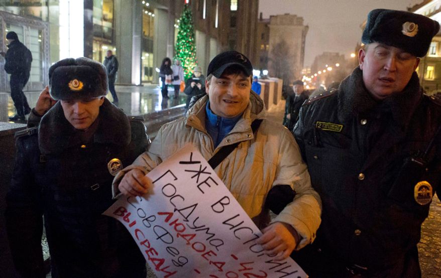 Russian police officers detain a demonstrator protesting outside the Russian parliament's upper chamber in Moscow on Dec. 26, 2012, against a bill banning U.S. adoptions of Russian children. (Associated Press)