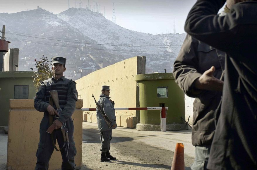 Afghan policemen stand guard outside of Kabul police headquarters, where a an American adviser was killed, in Kabul, Afghanistan, Monday, Dec. 24, 2014. An Afghan policewoman killed an American adviser at the Kabul police headquarters on Monday, a senior Afghan police official said. (AP Photo/Musadeq Sadeq)