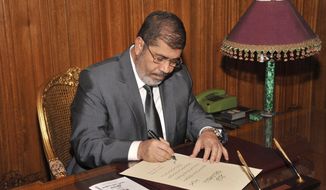 Egyptian President Mohammed Morsi signs into law the country&#39;s new Islamist-backed constitution late on Tuesday, Dec. 25, 2012. (AP Photo/Egyptian Presidency)
