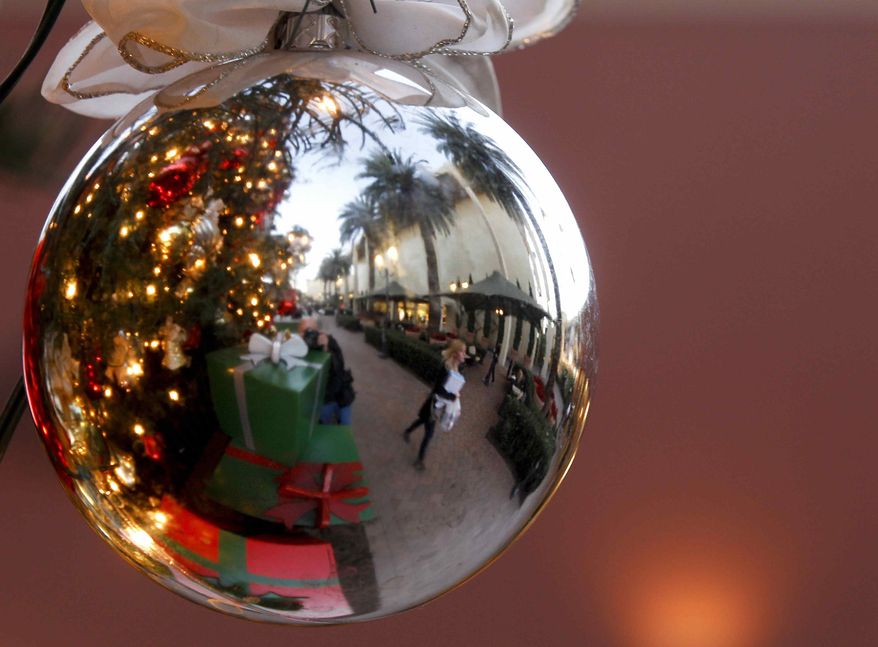 In this Thursday, Dec. 20, 2012, photo, a holiday shoppers reflected in a ornament handing from a large Christmas tree at Fashion Island shopping center in Newport Beach, Calif. Thursday, Dec. 20, 2012. U.S. holiday retail sales this year are the weakest since 2008, after a shopping season disrupted by storms and rising uncertainty among consumers. (AP Photo/Chris Carlson)