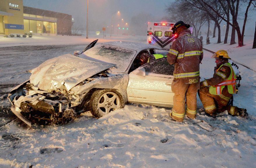 Rescuers work to move a driver injured in a wreck on a slick, snow-covered street in Columbus, Ind., Wednesday, Dec. 26, 2012. The blizzard warning issued the day before by National Weather Service came to fruition in the region Wednesday as winds picked up and snow began falling in earnest before dawn. (AP Photo/The Republic, Joe Harpring)