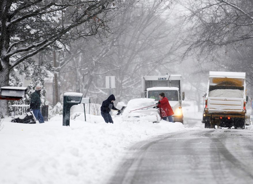 Residents clear cars and driveways as plows clear the streets in Carbondale, Ill. on Wednesday, Dec. 26, 2012. A gusty winter storm slammed southern Illinois on Wednesday, leaving roads covered in ice and snow and prompting authorities to warn of whiteout conditions that could significantly reduce drivers' visibility. (AP Photo/ The Southern Illinoisan, Aaron Eisenhauer)