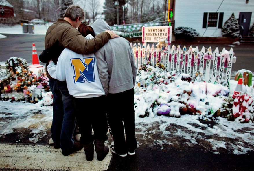 Members of the Rutter family of Sandy Hook, Conn., embrace early Christmas morning as they stand near memorials by the Sandy Hook firehouse in Newtown, Conn.,Tuesday, Dec. 25, 2012. People continue to visit memorials after gunman Adam Lanza walked into Sandy Hook Elementary School in Newtown, Conn., Dec. 14, and opened fire, killing 26, including 20 children, before killing himself. (AP Photo/Craig Ruttle)