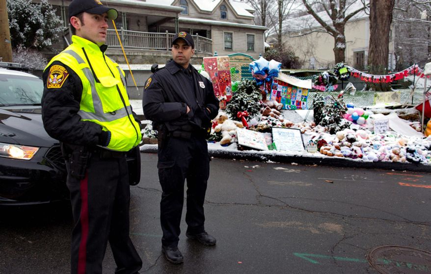 From left, Town of Ridgefield, Conn., Det. Durling, and Town of Greenwich, Conn., Officer Rivera stand near a memorial in Newtown, Conn. Tuesday, Dec. 25, 2012. Regional police agencies arrived in Newtown to relieve the local police force for the Christmas holiday. (AP Photo/Craig Ruttle)