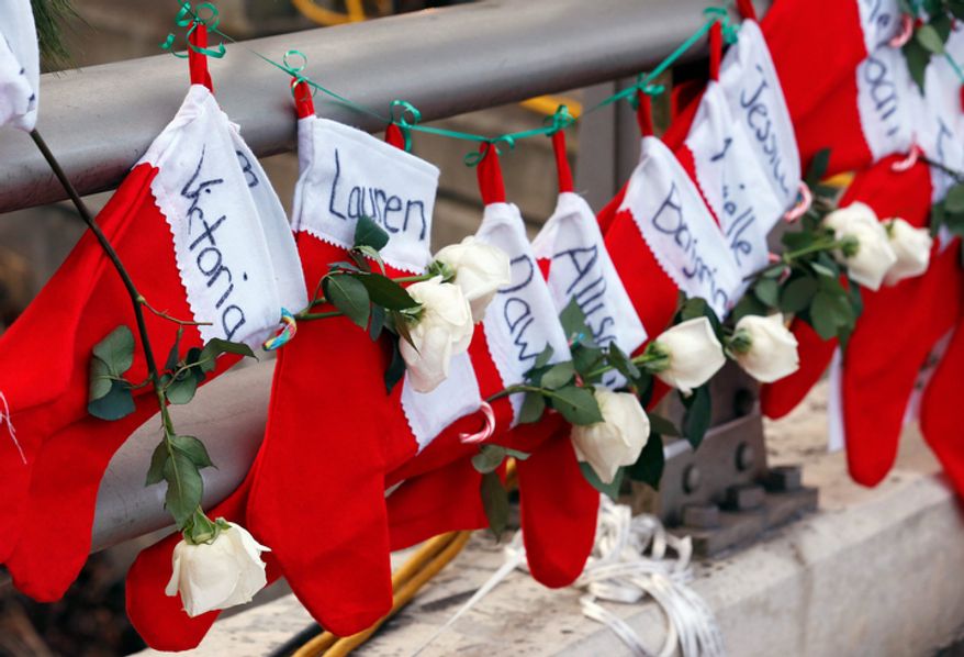 In this Wednesday, Dec. 19, 2012 file photo, Christmas stockings with the names of shooting victims hang from railing near a makeshift memorial near the town Christmas tree in the Sandy Hook village of Newtown, Conn. (AP Photo/Julio Cortez, File)