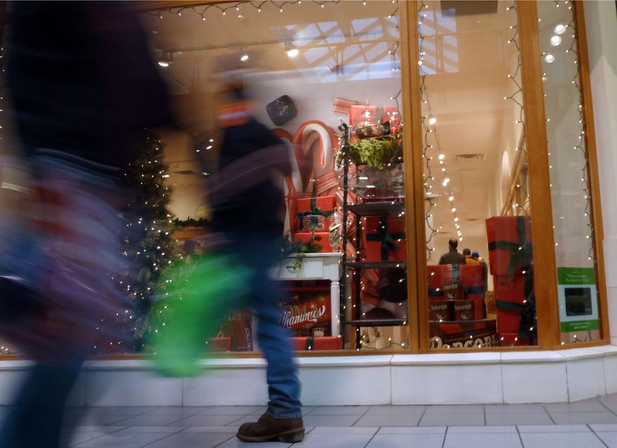 Christmas shoppers walk past a store at a mall in Salem, N.H., on Friday, Dec. 21, 2012. (AP Photo/Elise Amendola)