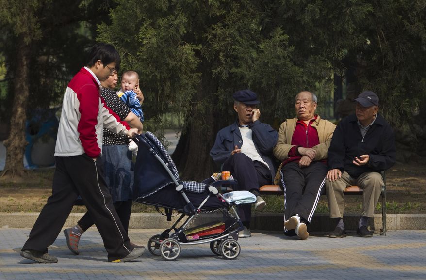 **FILE** Elderly men rest on a bench April 28, 2011, as a family with their new born baby walk past at a park in Beijing. (Associated Press)