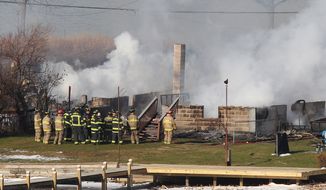 **FILE** Firefighters gather around a burning house after they were let back into the area to battle the blaze on Dec. 24, 2012, in Webster, N.Y. A gunman ambushed four volunteer firefighters responding to the fire, killing two and ending up dead himself, authorities said. (Associated Press/Democrat &amp; Chronicle)