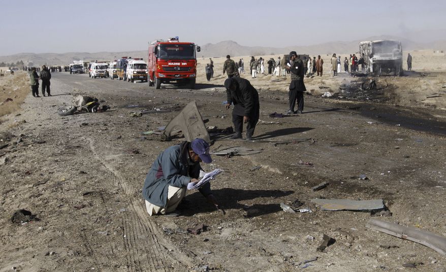 Pakistani police officers collect evidence from the site of a suicide bombing in Quetta, Pakistan, on Sunday, Dec. 30, 2012. A suicide bomber driving a pickup truck packed with explosives rammed into a bus carrying Shiite Muslim pilgrims in the country's southwest, killing 19 people, a government official and eyewitnesses said. (AP Photo/Arshad Butt)