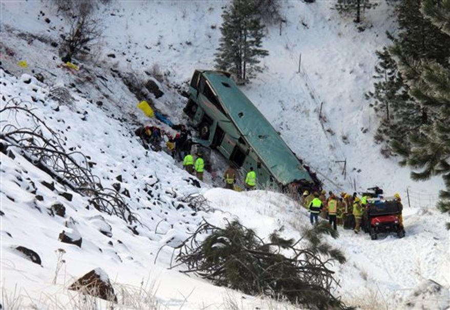Emergency personnel respond to the scene of a multiple-fatality accident where a tour bus careened through a guardrail along an icy highway and several hundred feet down a steep embankment, authorities said, Sunday, Dec. 30, 2012 about 15 miles east of Pendleton, Ore. The charter bus carrying about 40 people lost control around 10:30 a.m. on the snow- and ice-covered lanes of Interstate 84, according to the Oregon State Police. (AP Photo/East Oregonian, Tim Trainor)