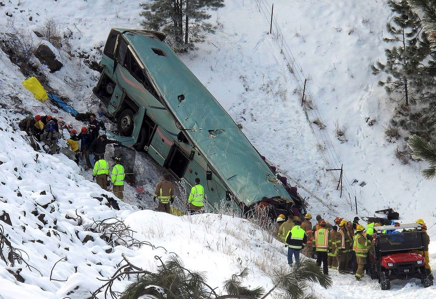 Emergency personnel respond to the scene of a multiple-fatality accident after a tour bus careened through a guardrail along an icy highway and fell several hundred feet down a steep embankment, authorities said, Sunday, Dec. 30, 2012 about 15 miles east of Pendleton, Ore. The charter bus carrying about 40 people lost control around 10:30 a.m. on the snow- and ice-covered lanes of Interstate 84, according to the Oregon State Police. (AP Photo/East Oregonian, Tim Trainor)