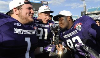 Northwestern defensive lineman Brian Arnfelt (91) and Bo Cisek (1) holds the trophy while their teammate Will Hampton (92) kisses it after the Gator Bowl NCAA college football game against Mississippi State, Tuesday, Jan. 1, 2013 in Jacksonville, Fla. Northwestern won 34-20.  (AP Photo/Stephen Morton)