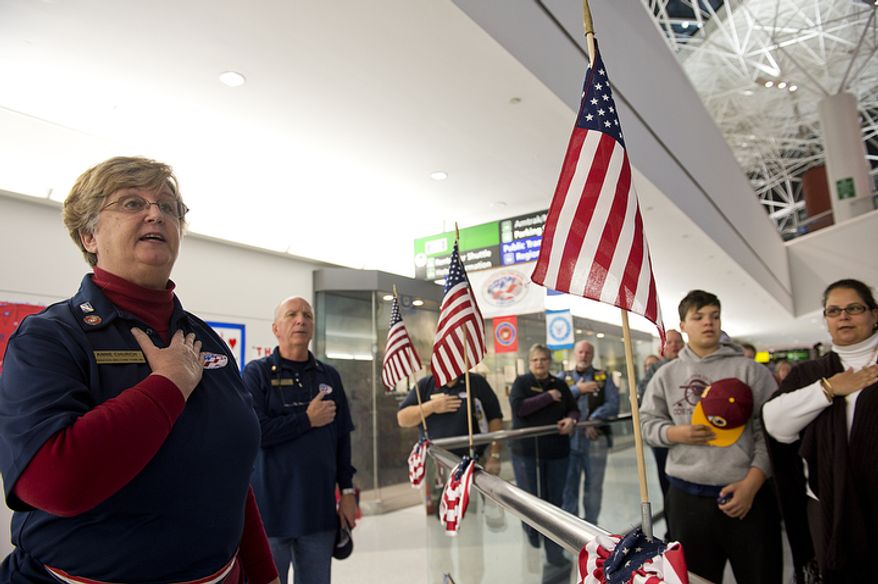 ** FILE ** Operation Welcome Home Maryland team leader Anne Church, left, leads volunteers and friends and family in the Pledge of Allegiance before the arrival of a Delta charter flight bringing troops home at BWI Thurgood Marshall Airport in Baltimore, Md., on Friday, Dec. 28, 2012. (Barbara L. Salisbury/The Washington Times)