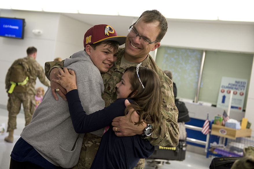 Charles and Caroline Brennikmeyer of Falls Church, Va. hug their dad, Maj. Oscar Brennikmeyer, U.S. Air Force, after he arrives on a military charter flight home from a six-month deployment in Afghanistan at BWI Thurgood Marshall Airport on Friday, Dec. 28, 2012. Friday was Charles' 14th birthday, and he said having his dad home was the best birthday gift ever. (Barbara L. Salisbury/The Washington Times)