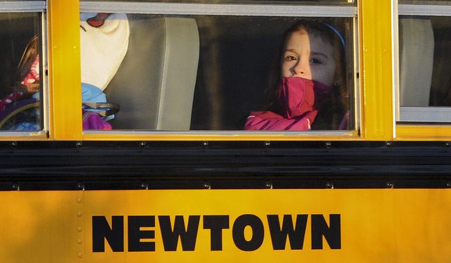 **FILE** A girl sits on a Newtown bus leaving the new Sandy Hook Elementary School after the first day of classes in Monroe, Conn., on Jan. 3, 2013. The Sandy Hook students started that day in their new school, formerly called Chalk Hill School in Monroe. It was renamed Sandy Hook Elementary and overhauled especially for the students from the Sandy Hook School shooting. (Associated Press)