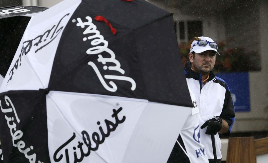 Ben Curtis peers from behind an umbrella protecting him from a driving side-wind as he prepares to tee off on the first hole at the Tournament of Champions golf tournament Friday, Jan. 4, 2013, in Kapalua, Hawaii. The tournament day was scratched later because of wind and rain. (AP Photo/Elaine Thompson)