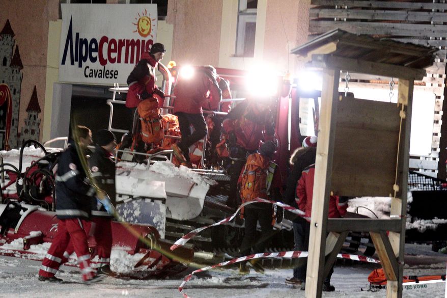 Rescue workers recover the bodies of six people who died following a sled crash on Mount Cermis, northern Italy, early Saturday, Jan. 5, 2013. Six Russians were killed and two others were injured late Friday after their snowmobile slammed into a fence and flipped over into a ditch during a night run down an Italian ski slope. (AP Photo/Federico Modica)