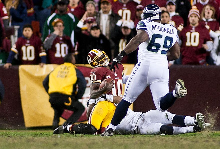Washington Redskins quarterback Robert Griffin III (10) is hit hard in the fourth quarter and is later taken out with an injury to his knee against the Seattle Seahawks in the NFC wild card game at FedEx Field, Landover, Md., Sunday, January 6, 2013. (Craig Bisacre/The Washington Times)