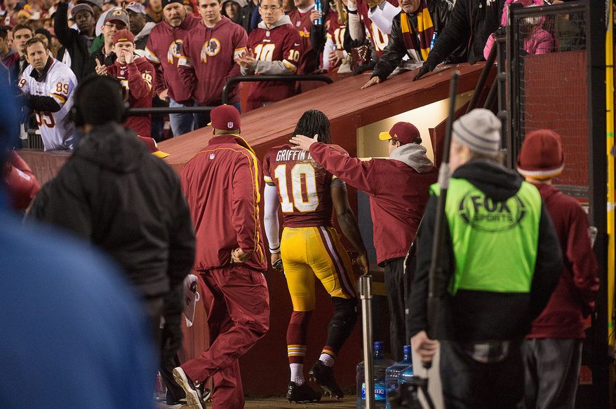 Medical staff members take Griffin into a sideline training room to look at his injured knee late in the fourth quarter Sunday. Coach Mike Shanahan said Monday the extent of the injury remains unknown. (Andrew Harnik/The Washington Times)