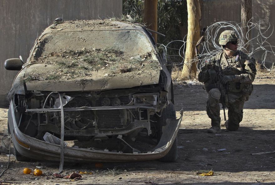 A U.S. soldier with the NATO-led International Security Assistance Force (ISAF) investigates the scene after two suicide attacks in Spin Boldak, Kandahar province, south of Kabul, Afghanistan, Sunday, Jan. 6, 2013. Two suicide bombers penetrated a government compound in the country's south Sunday, killing several, Afghan officials said. There were no reports of foreign troops or civilians at the site. (AP Photo/Allauddin Khan)