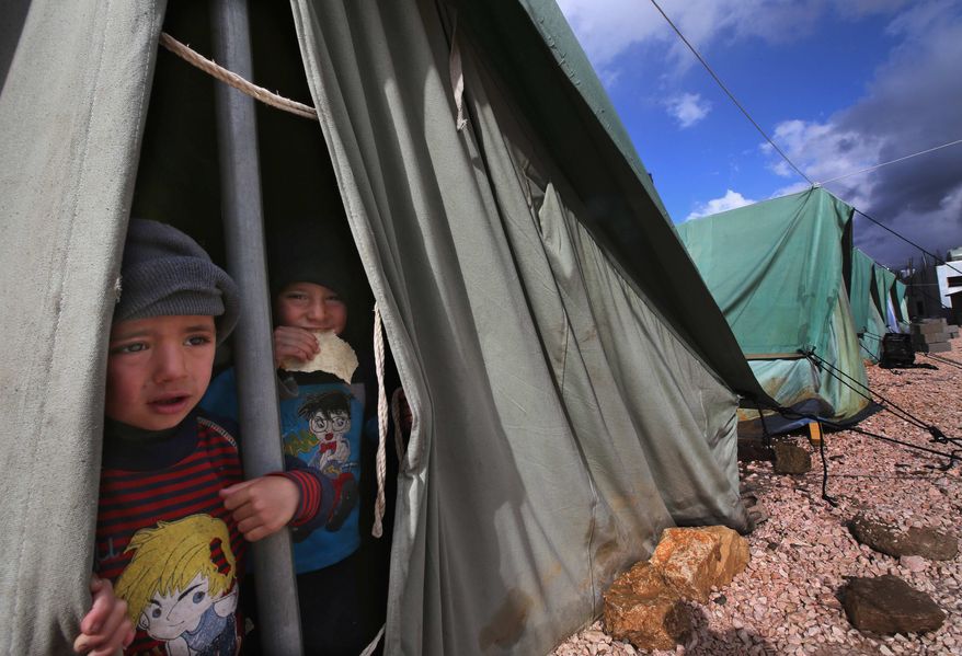 Syrian refugee boys look Jan. 7, 2013, outside their tent at a temporary refugee camp in the eastern Lebanese town of Marj near the border with Syria. (Associated Press/File)