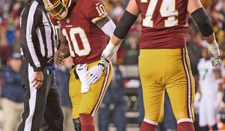 Redskins tackle Tyler Polumbus (74) helps a hobbled Robert Griffin III after the quarterback was shaken up on an illegal hit in the first quarter. Griffin had first aggravated his injured right knee two plays earlier on a rollout. (Andrew Harnik/The Washington Times)