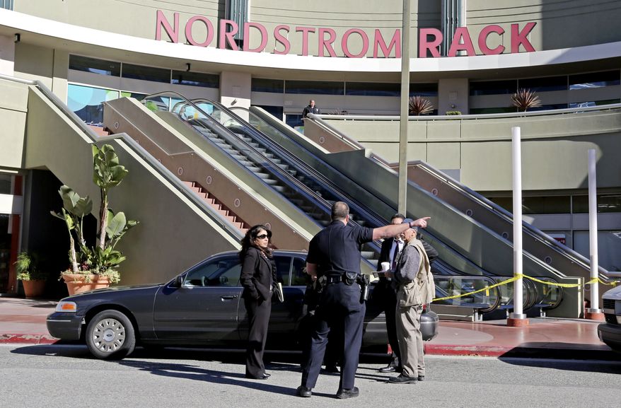Los Angeles police investigators stand outside a Nordstrom Rack store at Howard Hughes Center near Los Angeles International Airport Friday, Jan. 11, 2013. Robbers stabbed a clothing store employee and sexually assaulted another during an hours-long hostage drama that ended early Friday with a police SWAT team surging into the shop and rescuing 14 workers. (AP Photo/Reed Saxon)